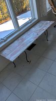 Full view of marble slab table against window, showing the overall length and finish of the marble top.