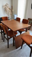 Table with pull-out leaf partially inserted, six chairs arranged around