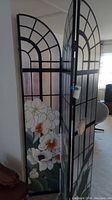 Shows the floral design with white orchids and arched black metal framing on the room divider.