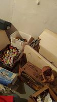 Wide view showing multiple boxes and bins containing vintage dolls, toy accessories, and packaging including Sunshine Farm box.