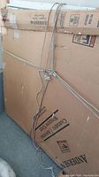 Large cardboard box containing Anderson casement/awning window unit tied with rope.