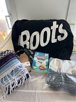 Photo of all items laid out on bed: black Boots sweatshirt, Mexican blanket, slippers in package, coasters, socks.