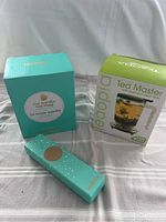 Photo of three boxed items: David's Tea Nordic mug box, Teaopia Tea Master teapot box, and David's Tea gold perforated spoon box.