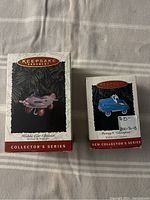 Photo of two Hallmark Keepsake Collector's Series boxed ornaments: Murray Airplane and Murray Champion Kiddie Car.