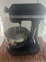 Front-left angle view of black mixer with bowl and whisk installed