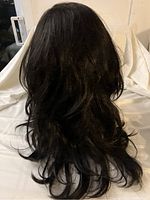 Front and side views of long black synthetic wig with soft curls, displayed on a mannequin head with white backdrop.
