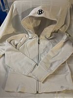 White Lululemon Scuba hoodie laid flat showing front and full sleeves.