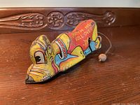 Front angled view of the Pluto tin toy showing detailed paint and pull string.