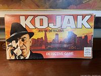 Box cover featuring Kojak detective with telephone and city skyline background