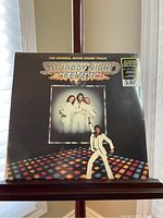 Front cover of the Saturday Night Fever soundtrack vinyl showing title, disco-themed artwork, and characters.