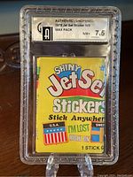 Photo of the 1975 Jet Set Stickers unopened wax pack in a clear graded case showing the front label and the pack's colorful design.
