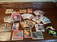 Overview of assortment of vintage non-sport trading cards laid out on a carved wooden surface, showing cards from various TV shows and flags collection.