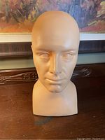 Front view of beige mannequin head showing facial details and smooth surface.