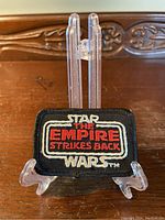 Front view of the embroidered patch showing the Star Wars The Empire Strikes Back logo on black fabric.