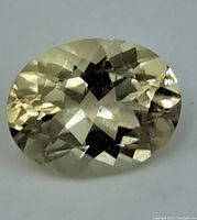 Top-down view of the oval citrine gemstone showing multi-faceted checkerboard cut and pale yellow color.