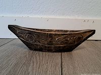 Side view of the carved wooden boat figurine showing detailed patterns and overall shape