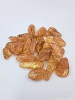 Multiple polished brown agate stones laid on plain white background, showing translucent amber tones and varied shapes.