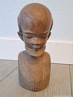 Front view of wooden African man statue showcasing detailed facial features, beard, and textured carving on the bust base.