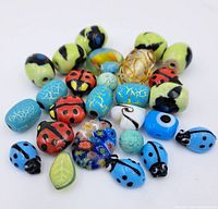 Photo of assorted mixed porcelain and glass beads including ladybug shapes, floral millefiori and crackled turquoise beads on white background.