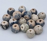 Close-up group of 17 round porcelain beads in blue, gray, and beige tones showing glaze and wear.