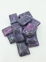 A cluster of several rectangular purple stone beads with patterned veining shown on a white surface.
