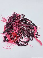 Multiple strands of garnet beads in a tangled pile showing various bead sizes and shapes on red threads.