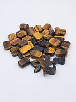 Cluster of polished tiger's eye beads with rectangular shapes showing characteristic golden brown and black chatoyancy.
