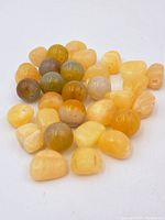 Photo showing a pile of about 40 yellow agate beads of different shapes and shades from pale to darker yellow and some with inclusions.