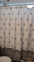 Shower curtain on rod with cream background and gray paisley border pattern