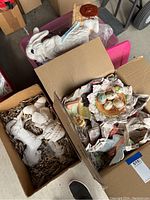 Box with additional unfinished white ceramic figurines and painted fairy figurine on pink container lid.