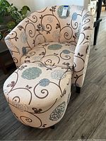 Front angle of upholstered chair and ottoman, showing floral pattern and condition