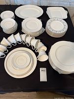 Overview of full white and silver china set with plates, teacups, saucers, and platters