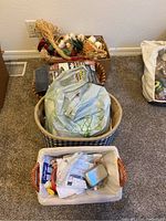 Photo showing baskets filled with various decor and sewing items including artificial floral pieces and packaged supplies.