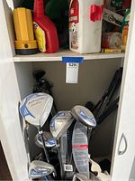 White cabinet lower shelf with multiple golf clubs, some Wilson brand visible