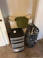 Photo of two hampers, a black plastic drawer organizer, and a green blanket on top of one hamper