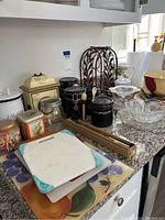 Overview of kitchen items on granite countertop including black canisters, cutting boards, ceramic and crystal bowls, and a bamboo wine rack.
