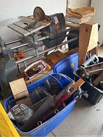 View of Shopsmith lathe with saw blade, multiple bins with accessories, wooden sawhorses, and booklets.