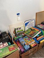 Photo showing a variety of jigsaw puzzles stacked in boxes including 1000-piece puzzles and art-themed covers