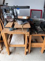 Sears Craftsman table saw with two attached tables on wooden stands. Various tools on and around the tables.