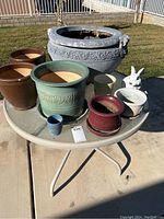 Photo showing round glass patio table with six of the pots and the rabbit figurine on top, outdoor setting.