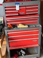 Front view of large red and gray Sears Craftsman tool box showing multiple locked drawers, some open to reveal tools and small hardware.