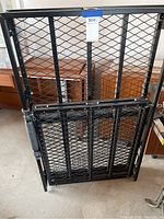 Folded black metal wheelchair ramp with mesh platform and side rails