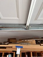 Photo showing a stack of various wooden boards and planks stored horizontally in a garage.