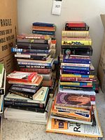 Photo showing two large stacks of assorted used books on a carpeted floor.