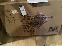 Photo of sealed cardboard box of Chair Gym System with label showing style number 9789TSFFCT and color purple, including some small packaged parts taped to the box.