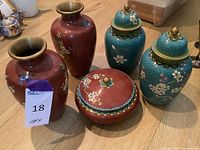 5 Chinese vintage cloisonné pieces including 2 red vases, 2 blue covered vases, and 1 red covered bowl shown together on table.