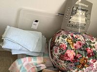 Image showing folded periwinkle blue bath and hand towels next to a floral comforter in its original packaging.