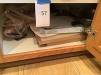 Various pans, cutting boards and CorningWare dishes stacked inside a wooden cabinet