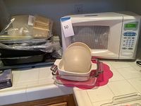 Magic Chef microwave, white, digital control panel, placed on countertop along with clear glass baking dishes and beige plastic containers.