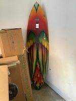 Front view of the surfboard showing colorful gradient and angel wings design, with visible size tags.
